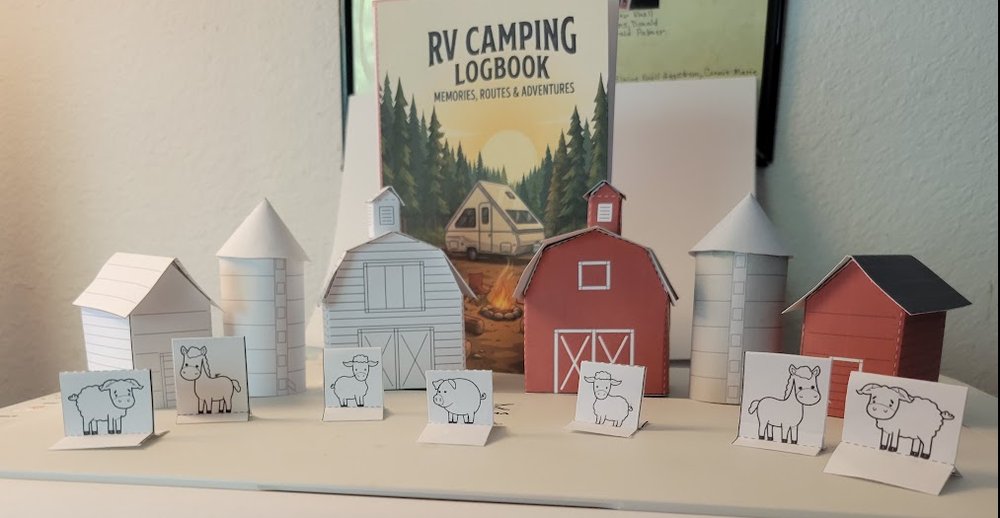 A papercraft farm: a red barn with a barn quilt, a white barn, two silos, a corn crib and fold-over farm animals, built from the free printables